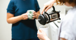 Person heller i kaffekopp. Foto.