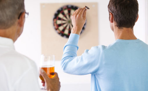 Foto: Man kaster på dartskive mens kollega ser på med en øl i hånden