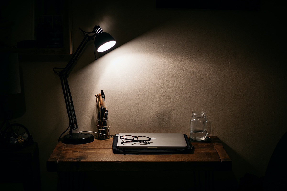 Arbeidspult med PC og lampe. Foto.