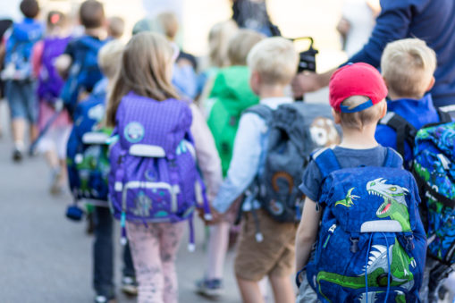 Foto: Mange barn på vei til skolen, alle med sekk på ryggen