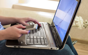 Foto: En hånd på pC-tastatur og den andre trykker på en iPhone