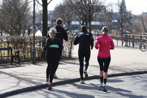 Foto; 4 personer jogger i by, alle med ryggen til