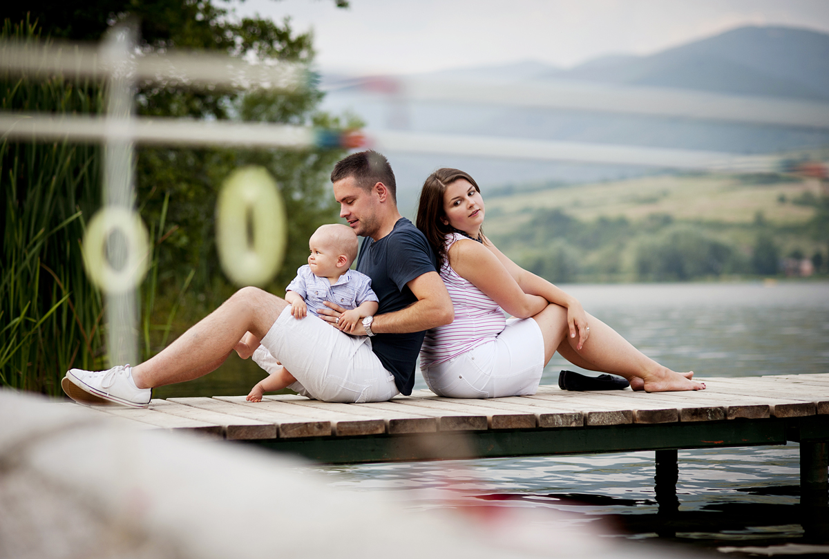 Foto: Famile på 3 med liten baby sitter på en brygge