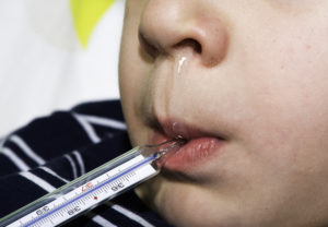 Foto: Sykt barn med rennende nese og febertermometer i munnen
