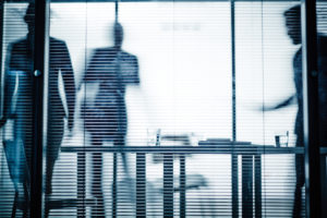 Foto: Personer på et kontor med glassvegger og fortrukkede persienner
