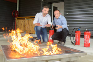 Foto: Brannøvelse, to menn med flammer og slukkeapparat
