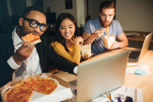 Foto: Kollegaer spiser pizza foran PC-er