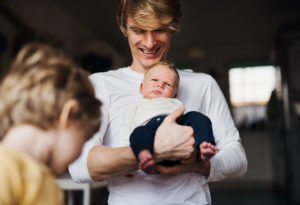 Foto: Far med baby i armene ser på et barn
