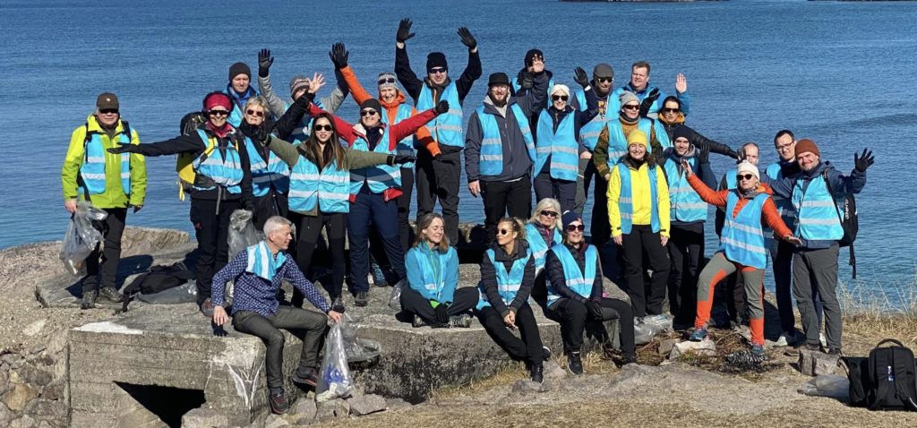 Foto: Gruppebilde Compendia-ansatte på et svaberg med sjø i bakgrunnen etter strandryddeaksjon