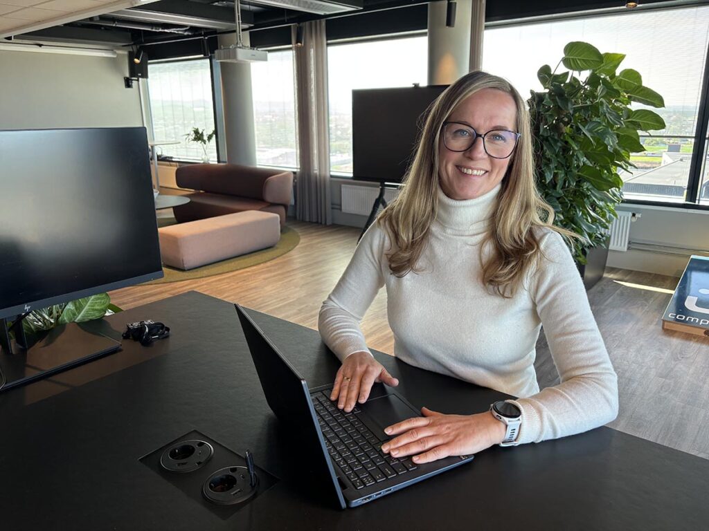 Dame med datamaskin står ved en pult