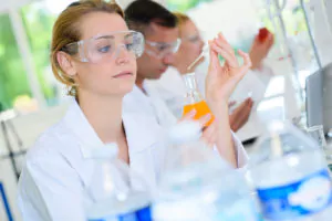Bilde: Dame med sikkerhetsbriller tar prøve på laboratorie