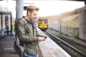 Foto: Mann står på perrongen og venter på toget som er på vei inn på stasjonen